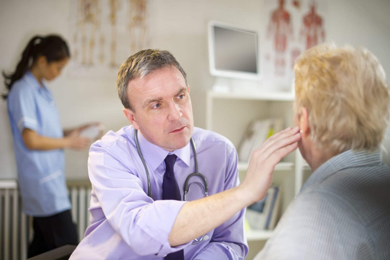 ENT Diagnosing Earwax Removal ENT inspecting an older patients ears for indications of an earwax blockage