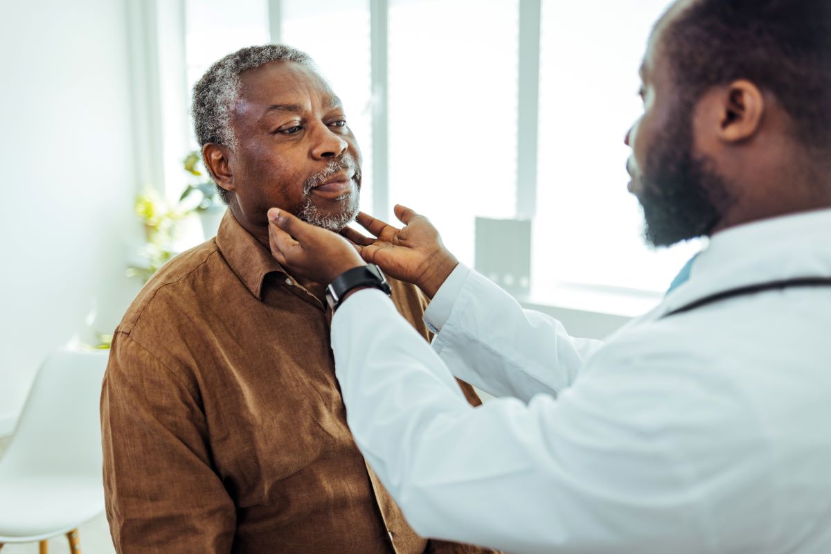 Doctor feeling a patients throat for symptoms of a sore throat