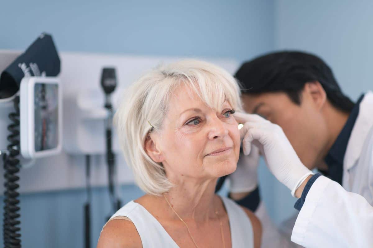 ear infection diagnosis male doctor looking older female patients ear for indications of an ear infection
