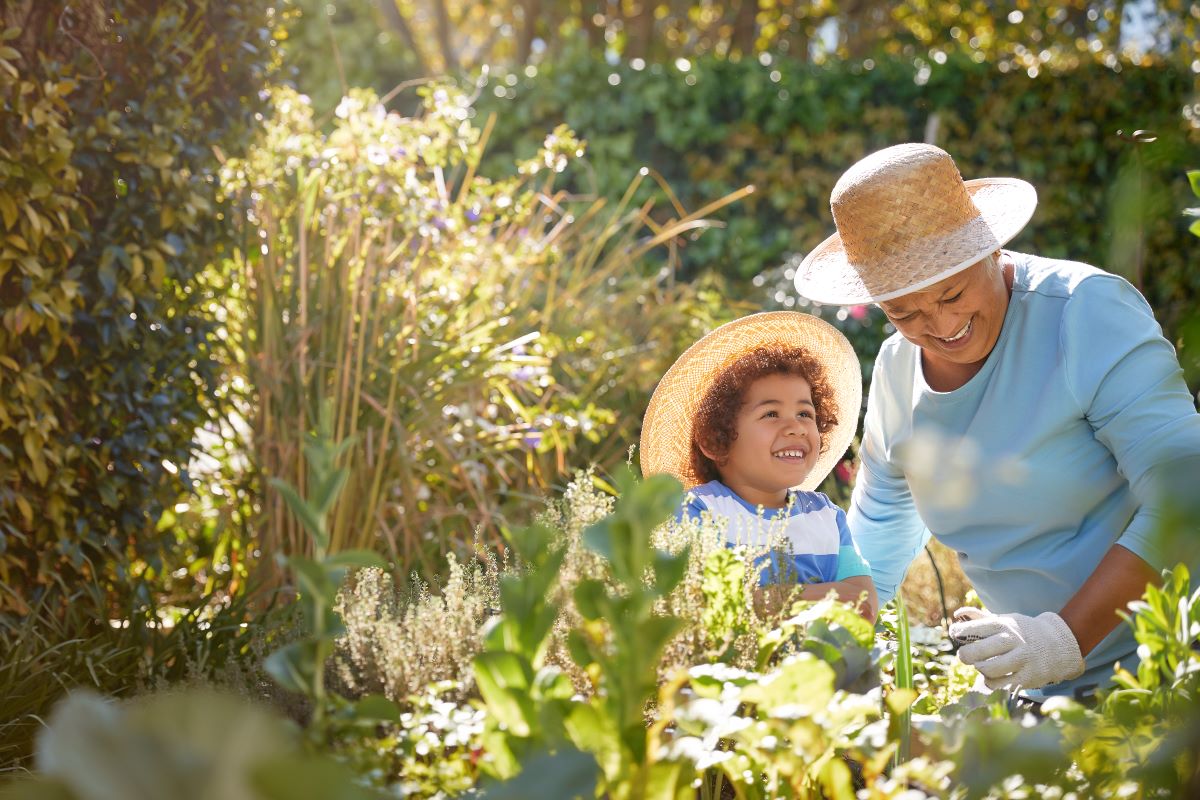A treated patient managing their allergy symptoms An older woman and child are outdoors gardening on a sunny day. They are wearing matching straw sunhats and the child looks up expectantly at the woman as she manipulates a plant while wearing yard work ready gloves.