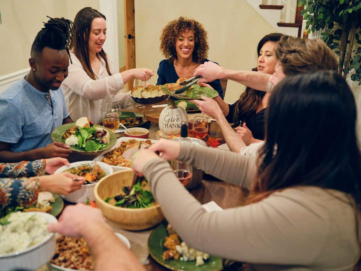 cause of gastroesophageal reflux disease Multi-ethnic group of friends are sharing a large dinner in a home dining area that includes mashed potatoes, stuffing, and salad. They are all smiling or mid laugh.
